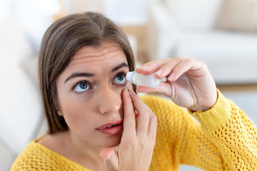 Mujer echándose gotas en los ojos antes de ponerse los lentes de contacto con aumento